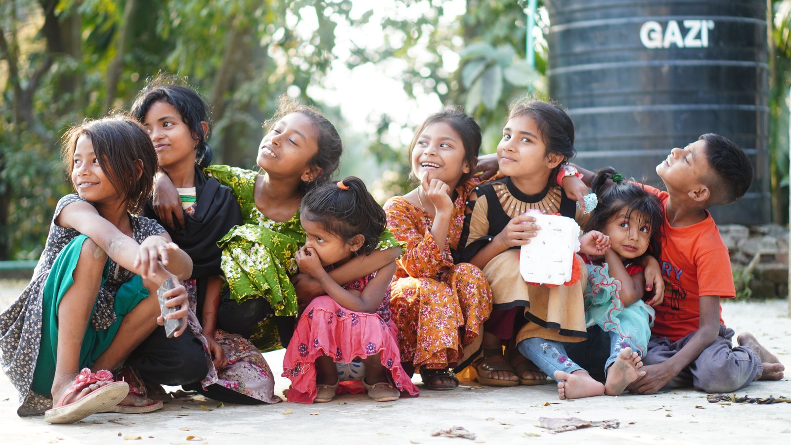 Children sitting together outdoors, representing the communities we serve