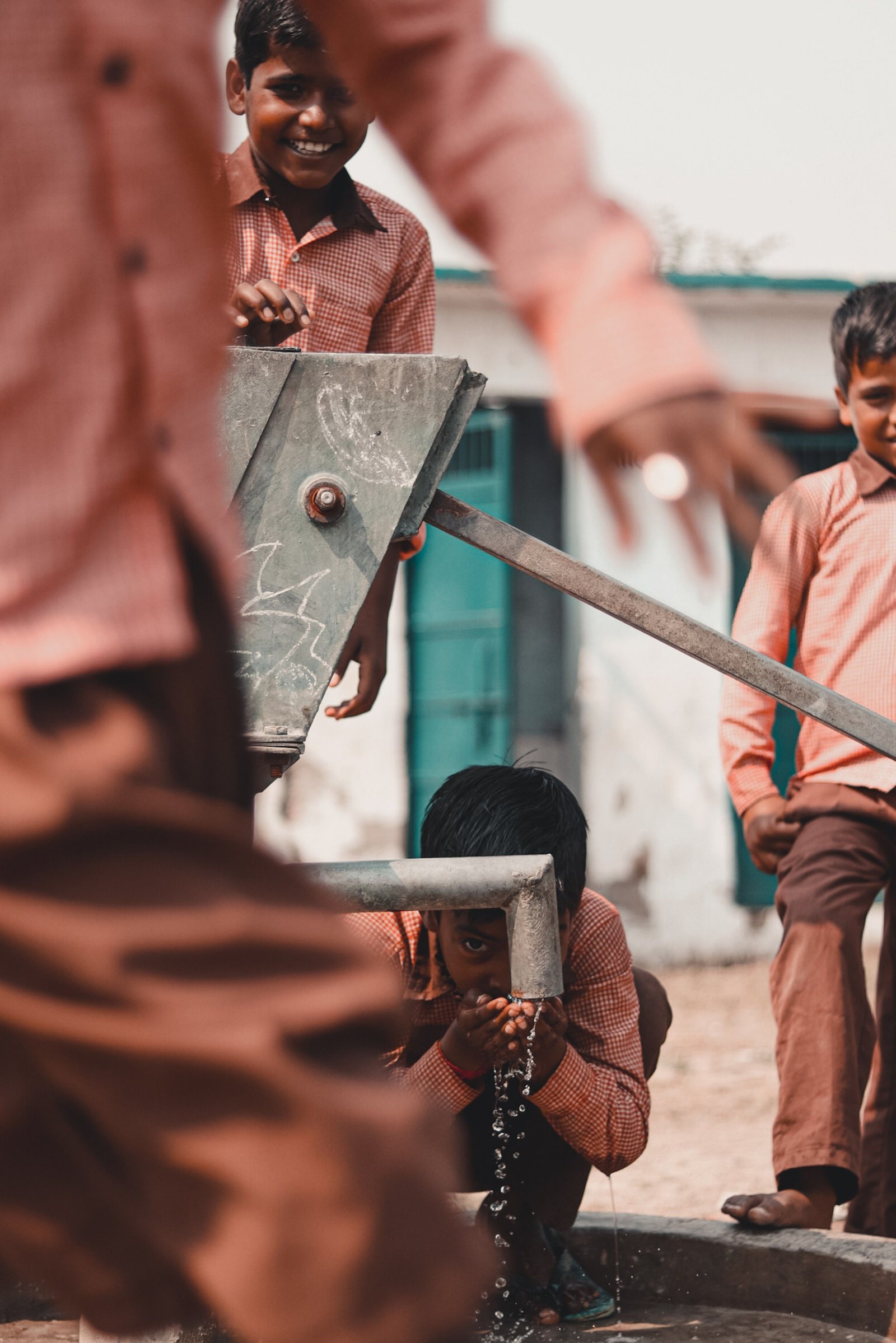 Schoolchildren collecting drinking water from a hand pump
