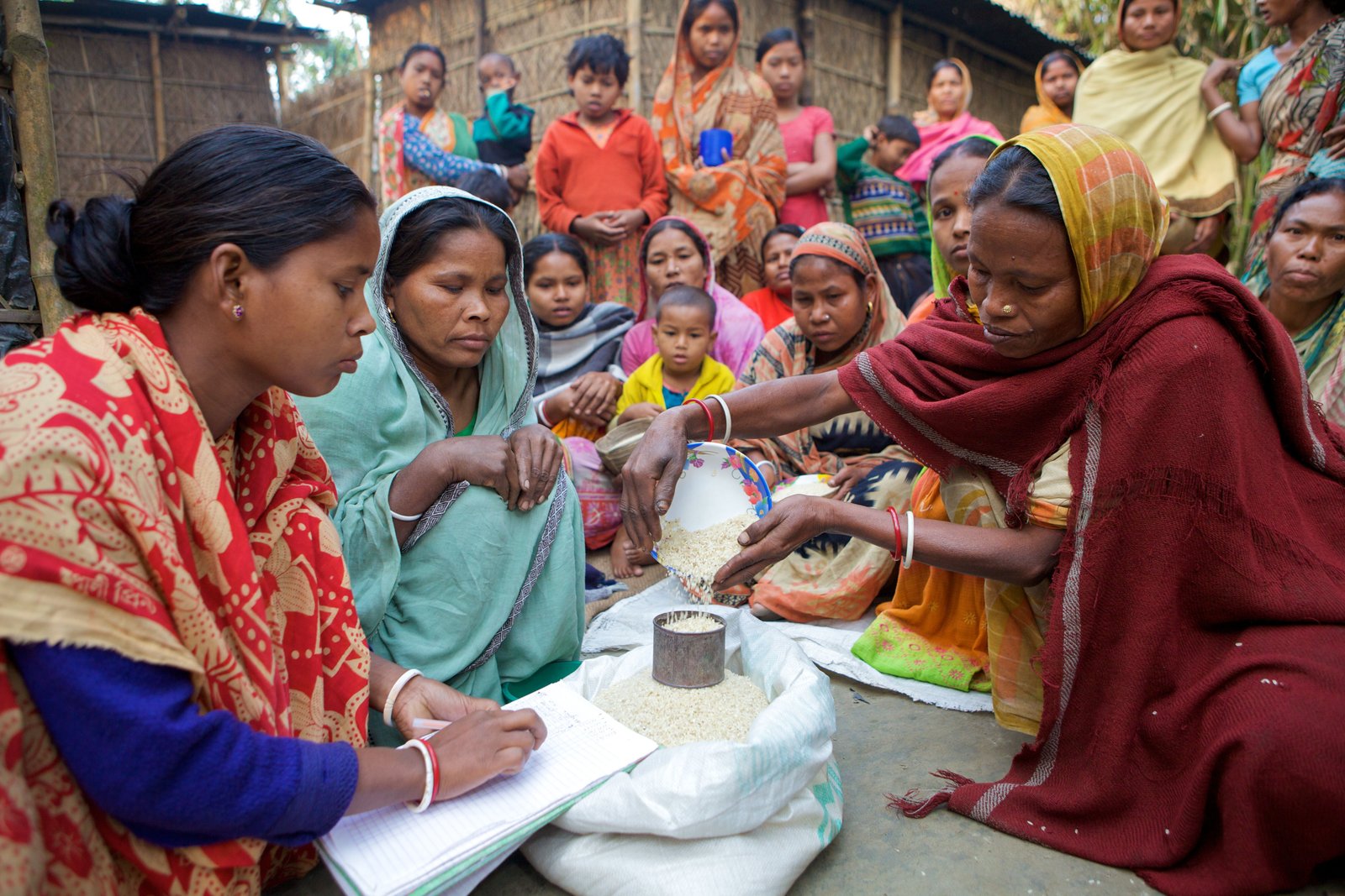 Women measuring and distributing grain during a community welfare activity
